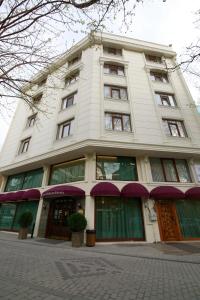 图兹拉Tuzla Garden Hotel & Spa的一座高大的白色建筑,设有绿色门窗