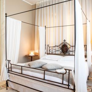 卡拉拉贝尔维多别墅精品酒店的卧室配有铁篷床和白色窗帘
