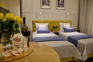 克拉科夫Bentis Luxury Apartments的客房设有三张床和一张带葡萄酒的桌子。