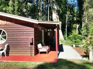 谭伯连山柯蒂斯小屋度假屋的小屋设有红色甲板和椅子
