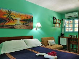 库尔克岛Sea Dreams Hotel的一间卧室配有一张床、一把椅子和一幅画