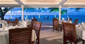 圣约翰斯Galley Bay Resort & Spa - All Inclusive - Adults Only的海滩上的餐厅,配有桌椅