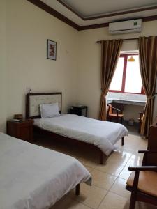海防Le Thanh Hotel的酒店客房设有两张床和窗户。