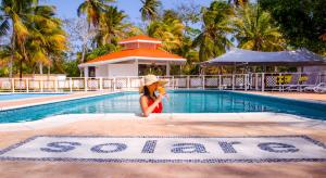 圣安德烈斯Solare SAI Ecohotel的坐在游泳池旁的戴帽子的女人