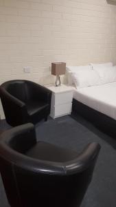阿德莱德Lockleys Hotel的一间卧室配有一张床和床边的椅子