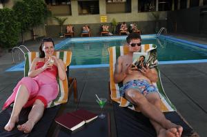 波隆纳鲁沃吉利托酒店的坐在游泳池旁草坪椅上的男女