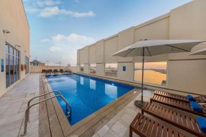 拉斯阿尔卡麦Citymax Hotel Ras Al Khaimah的一个带长椅和遮阳伞的游泳池