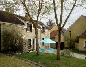 ReclosesCharmante Maison à Recloses的院子里带蓝色遮阳伞和椅子的房子