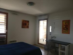马赛村庄酒店的一间卧室配有一张床、一张书桌和一个窗户。