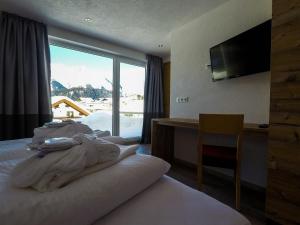瑙德斯Collina Hotel Garni的酒店客房设有一张带大窗户的床。
