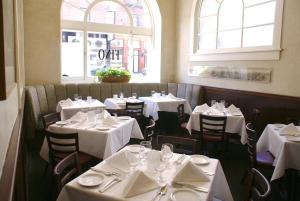 旧金山The Andrews Hotel的餐厅设有白色的桌椅和窗户。