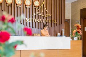 岘港Mitisa Hotel Da Nang的站在大厅柜台后面的女人