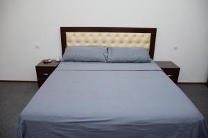 塔什干Nurziyo Guest House的一张带蓝色床单和两个床头柜的床和四柱床
