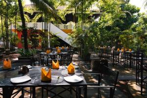 本托塔Amal Beach Hotel的一间设有桌椅的餐厅,种植了棕榈树