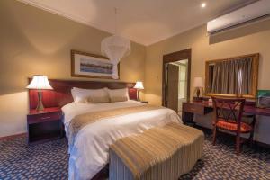 利隆圭太阳鸟首都酒店的酒店客房配有一张床、一张书桌和一张四柱床