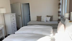 奥斯特巴特宁哈根里希特旅馆的一间白色卧室,配有两张床和镜子