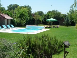 博讷Le Verger du Sausset的庭院内的游泳池配有椅子和遮阳伞