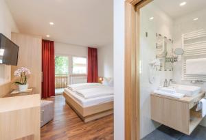 科莱伊萨尔科阿尔平戈珍酒店的一间卧室配有一张床,浴室设有水槽