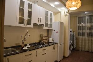 埃里温Massiv Apt的厨房配有白色橱柜、水槽和冰箱。