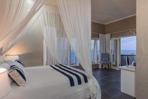 艾湄湾Bayu Cottages的一间卧室设有一张天蓬床,享有海景