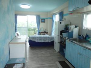石垣岛仲间由美酒店的厨房配有冰箱和窗户上的一张床