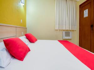 里约热内卢Hotel Villa Rica的卧室配有带红色枕头的大型白色床