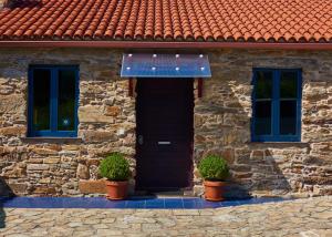 内安诺Pedracuca - Costa da Morte的一座石屋,有黑色的门和两棵植物