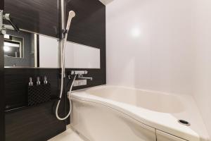 北九州GRAND BASE Mojiko的浴室设有白色浴缸,拥有黑色的墙壁