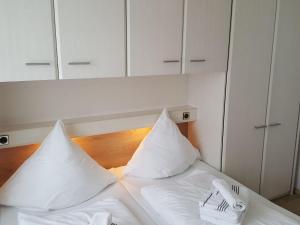 韦斯特兰Sylter-Besserburg-App-16的白色的床、白色枕头、叉子和餐巾