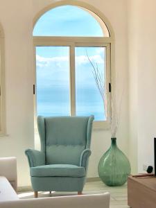 斯卡拉Sky House Amalfi Coast的窗前的蓝色椅子和花瓶