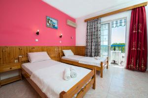阿彻奇洛斯Poseidon Apartment的配有两张床的带粉红色墙壁的客房