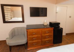 优马Budgetel Inn & Suites的一间卧室配有椅子和带电视的梳妆台