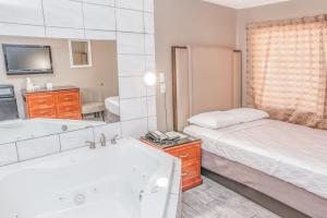 优马Budgetel Inn & Suites的一间卧室配有一张床、一个浴缸和一个水槽