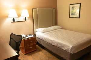 优马Budgetel Inn & Suites的酒店客房配有一张床、一张桌子和一部电话
