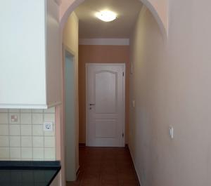 茨里克韦尼察Ivana apartman 3的一条带白色门的走廊和白色瓷砖地板