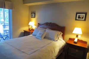 PiedmontAppart-hôtel Villégiature Saint-Sauveur的一间卧室配有一张带两盏灯的床和一个阳台