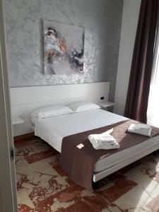 切萨雷奥港B&B L'Isola的卧室配有一张床,墙上挂有绘画作品