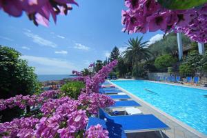 加尔尼亚诺帕拉吉纳酒店的一座拥有蓝色长椅和紫色花卉的游泳池