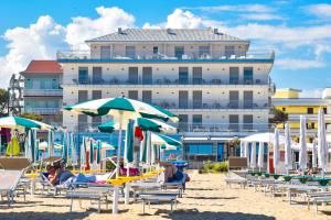 卡奥莱Hotel Delle Nazioni的一个带椅子和遮阳伞的海滩和一座建筑