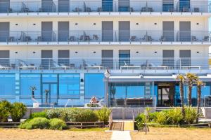 卡奥莱Hotel Delle Nazioni的海滩上带蓝色阳台的建筑