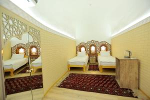希瓦Muso To'ra Hotel- boutique的一间设有两张床、一张桌子和一张地毯的房间