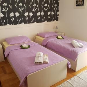 斯普利特Adela Apartments Žnjan Split的紫色床单的客房内的两张床