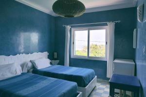 西迪考乌奇Blue Kaouki的一间蓝色卧室,配有两张床和窗户