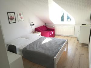 尤斯托尼莫斯基Pokoje Gościnne Abelard的一间卧室配有一张床和一张粉红色的椅子
