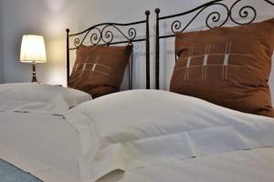 阿达玛斯奥斯提亚旅馆的一张带白色床单和枕头的床以及一盏灯
