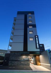 福冈One's Hotel Fukuoka的一座高大的黑色建筑,上面有标志