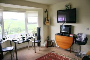 格林卡斯尔Wild Atlantic View Inishowen的一间设有一张桌子、一台电视和一张带吉他桌的房间