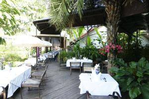 清莱清莱拉努纳度假酒店的一间设有白色桌椅和树的餐厅