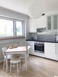 伯尔尼GreenPlace City Apartment的厨房配有白色橱柜和桌椅