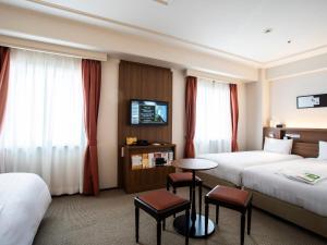 大阪新阪急大阪附楼酒店的酒店客房设有两张床和一张桌子。